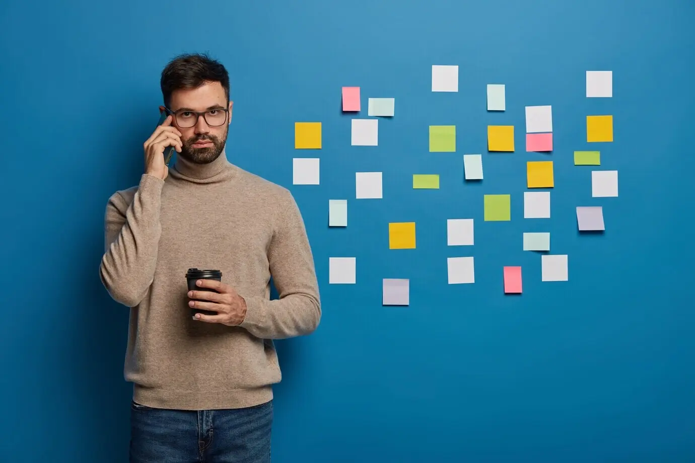 Бородатый мужчина организует свои задачи с помощью клейких заметок.